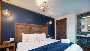Une chambre à coucher avec un grand lit, une tête de lit en bois, deux tables de chevet et une petite table de nuit avec une lampe.