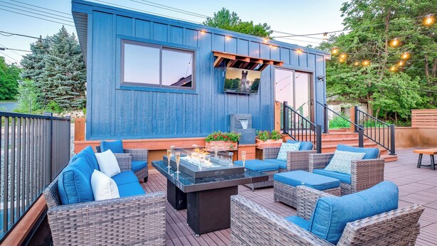 Une terrasse extérieure moderne, dotée de meubles en osier et d’un foyer intégré.