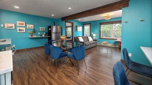 Une cuisine moderne avec un coin repas, un plancher en bois et des murs de couleur turquoise.