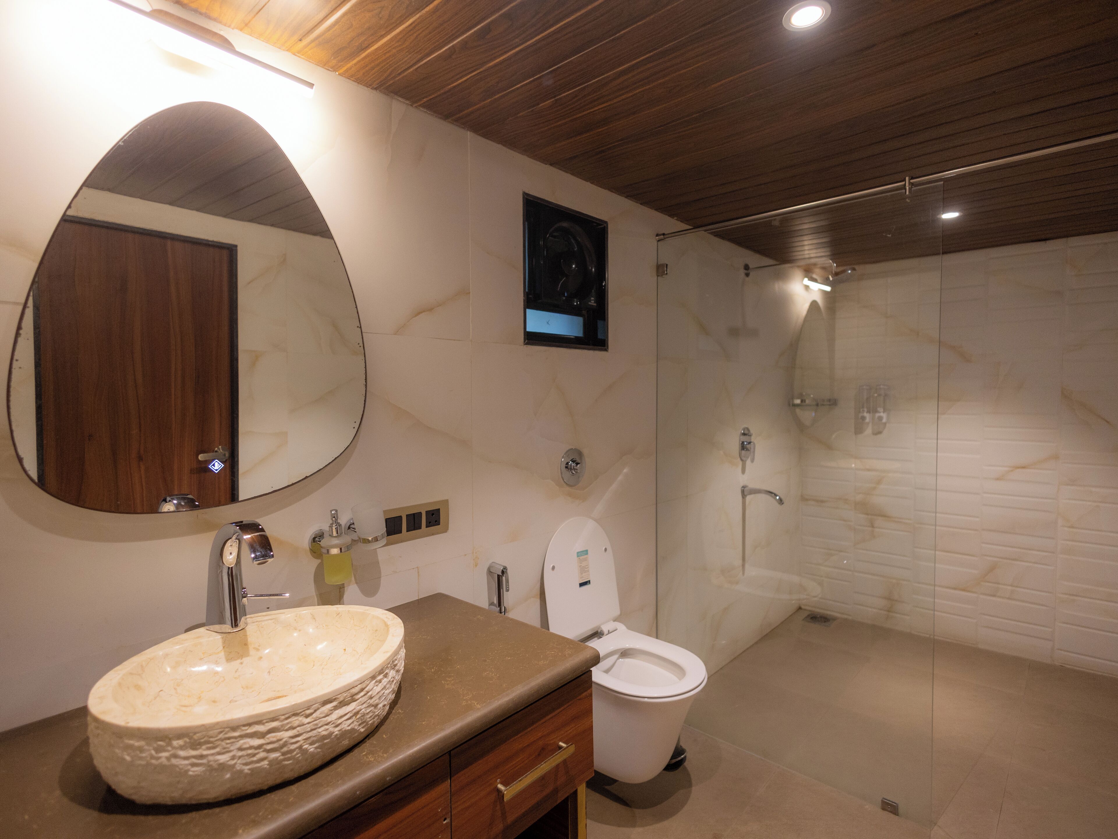 A modern bathroom with a large oval sink, a toilet, and a shower area.