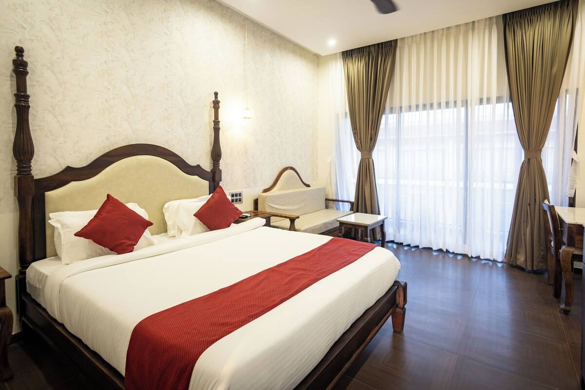 A hotel room with a large bed, a nightstand, a chair, a desk, and a ceiling fan.
