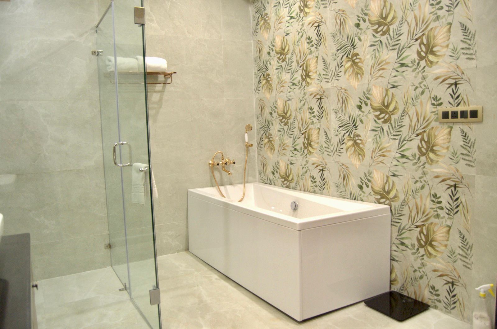 Un baño moderno con cabina de ducha de vidrio, una bañera blanca y un revestimiento de pared estampado con motivos florales.