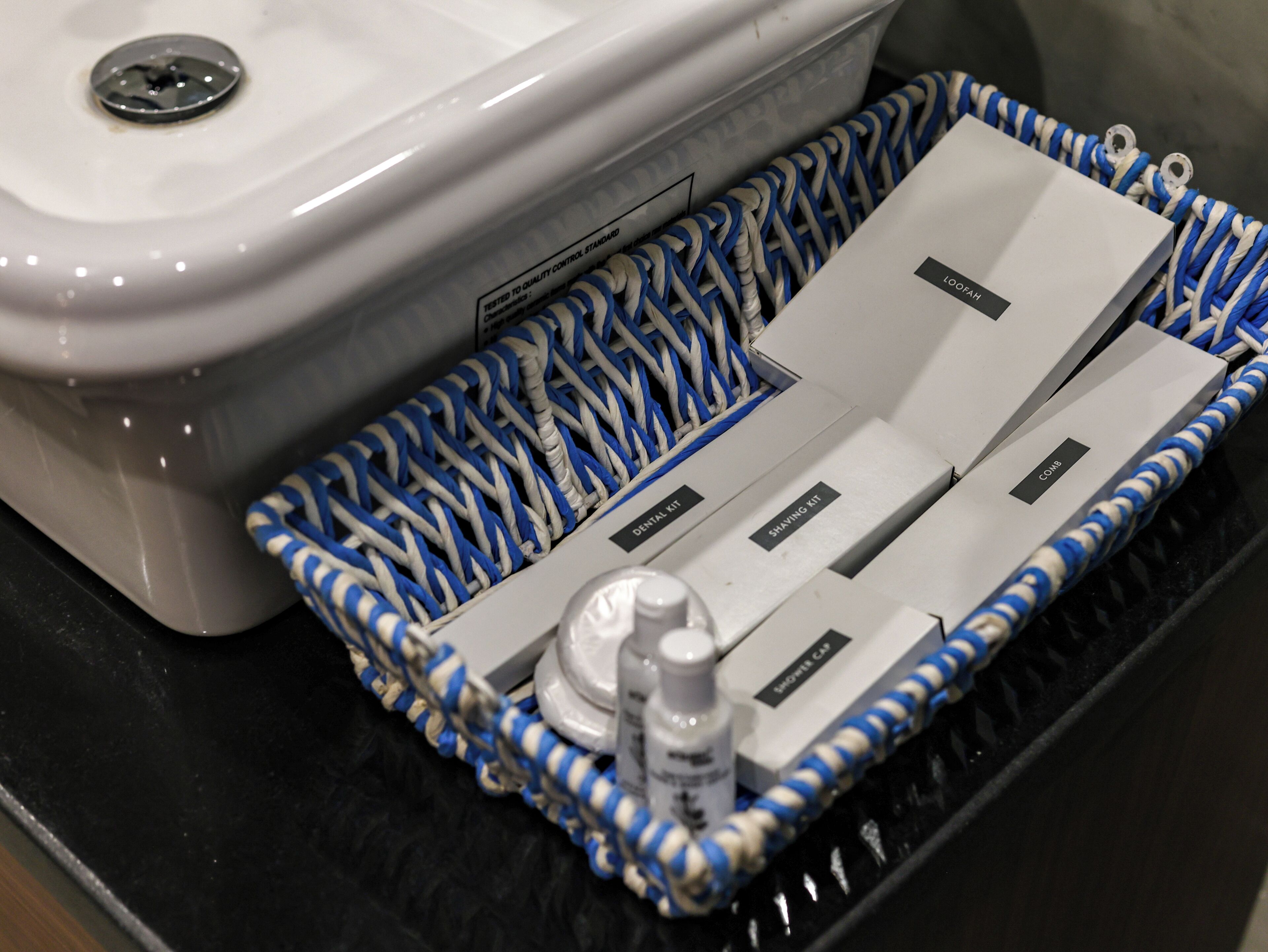 A bathroom with a white sink, a blue and white striped bath mat, and a white toilet.