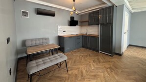 Uma cozinha moderna com piso em padrão herringbone, armários cinza e mesa de jantar de madeira com um banco.