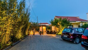 A paved driveway leading to a house with a red roof, surrounded by bamboo and potted plants. - Holiday Home Regina (Sibenik)