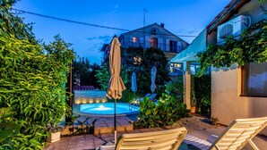 A backyard with a swimming pool, lounge chairs, and a house in the background. - Holiday Home Regina (Sibenik)