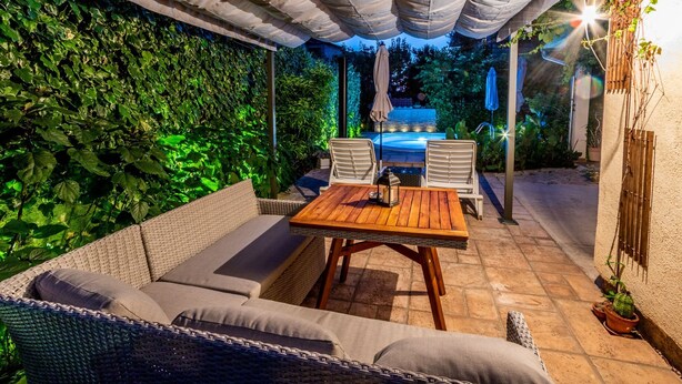An outdoor patio with a covered seating area, a pool, and lush greenery. - Holiday Home Regina (Sibenik)