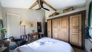 A hotel room with a large bed, wooden wardrobe, desk, chair, lamp, and radiator. - La Rose du petit Bois (Saint-Didier-au-Mont-d'Or)