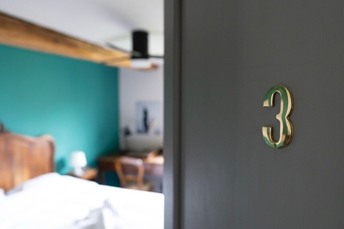 A room with a bed, a wooden headboard, and a teal wall.
