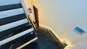 A staircase with a handrail, a fire extinguisher mounted on the wall, and a door at the top. - Hotel Shree (Ujjain)