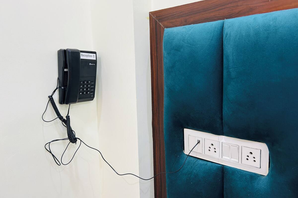 A reception phone mounted on a wall with a power outlet below it.