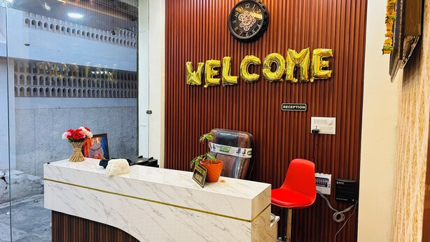 A reception desk with a marble top, a 'WELCOME' sign, a clock, and a reception sign. - Hotel Shree (Ujjain)
