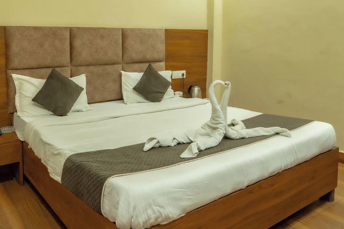 A neatly made bed with a wooden headboard, white bedding, and two pillows.