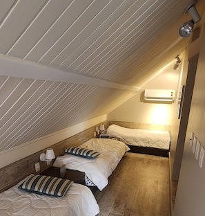 A narrow attic bedroom with sloped ceilings, two beds, and a wall-mounted air conditioner. - Malawi Resort (Ipojuca)