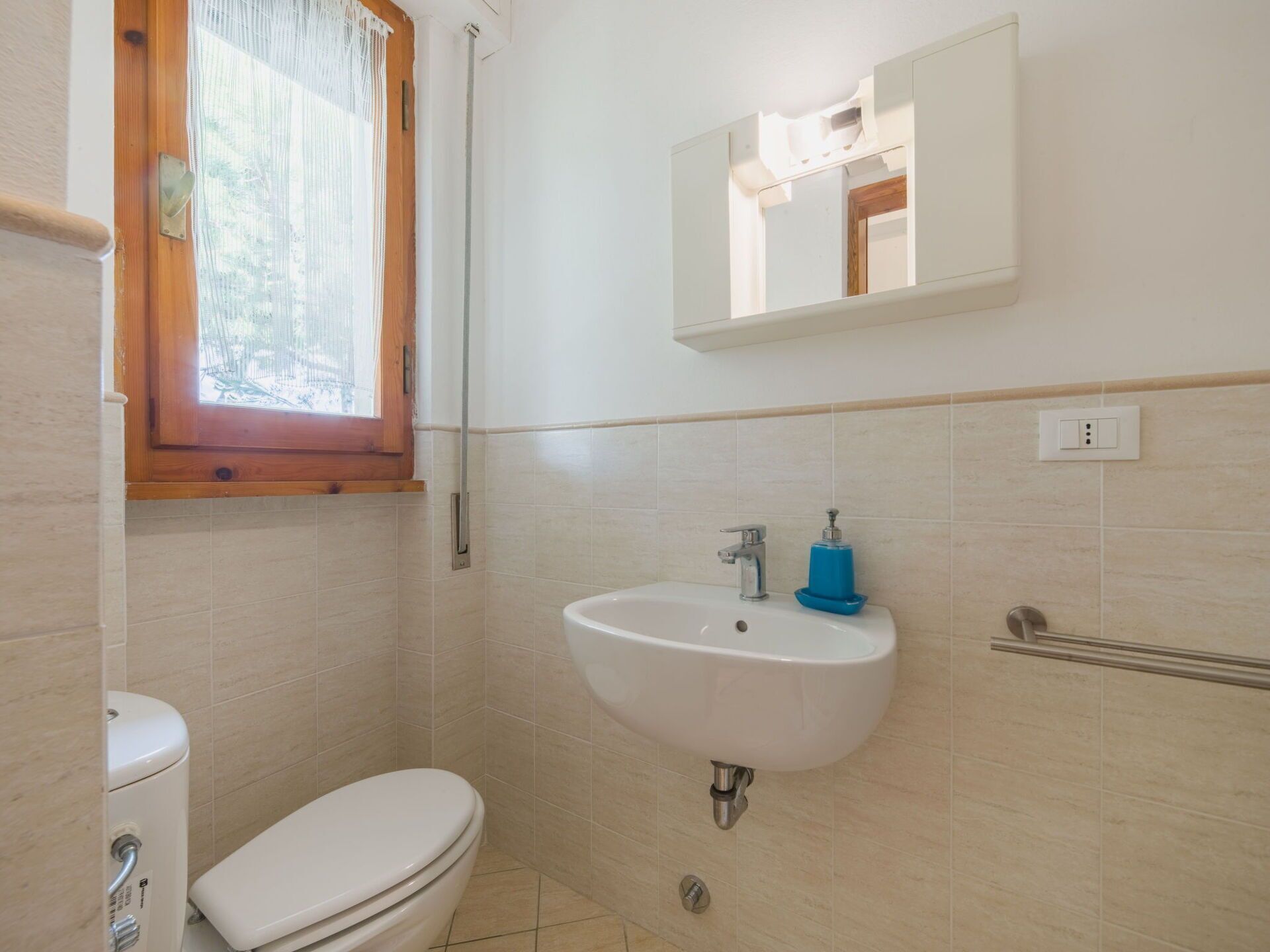 A small bathroom with a toilet, a sink, and a mirror.
