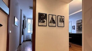 A hallway with wooden flooring, a door leading to another room, and three framed pictures on the wall. - Bright in Saint Ursula (Bergamo)