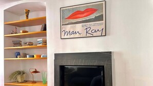 A living room with a fireplace, shelves with books and decorative items, and a framed artwork above the fireplace. - Bright in Saint Ursula (Bergamo)