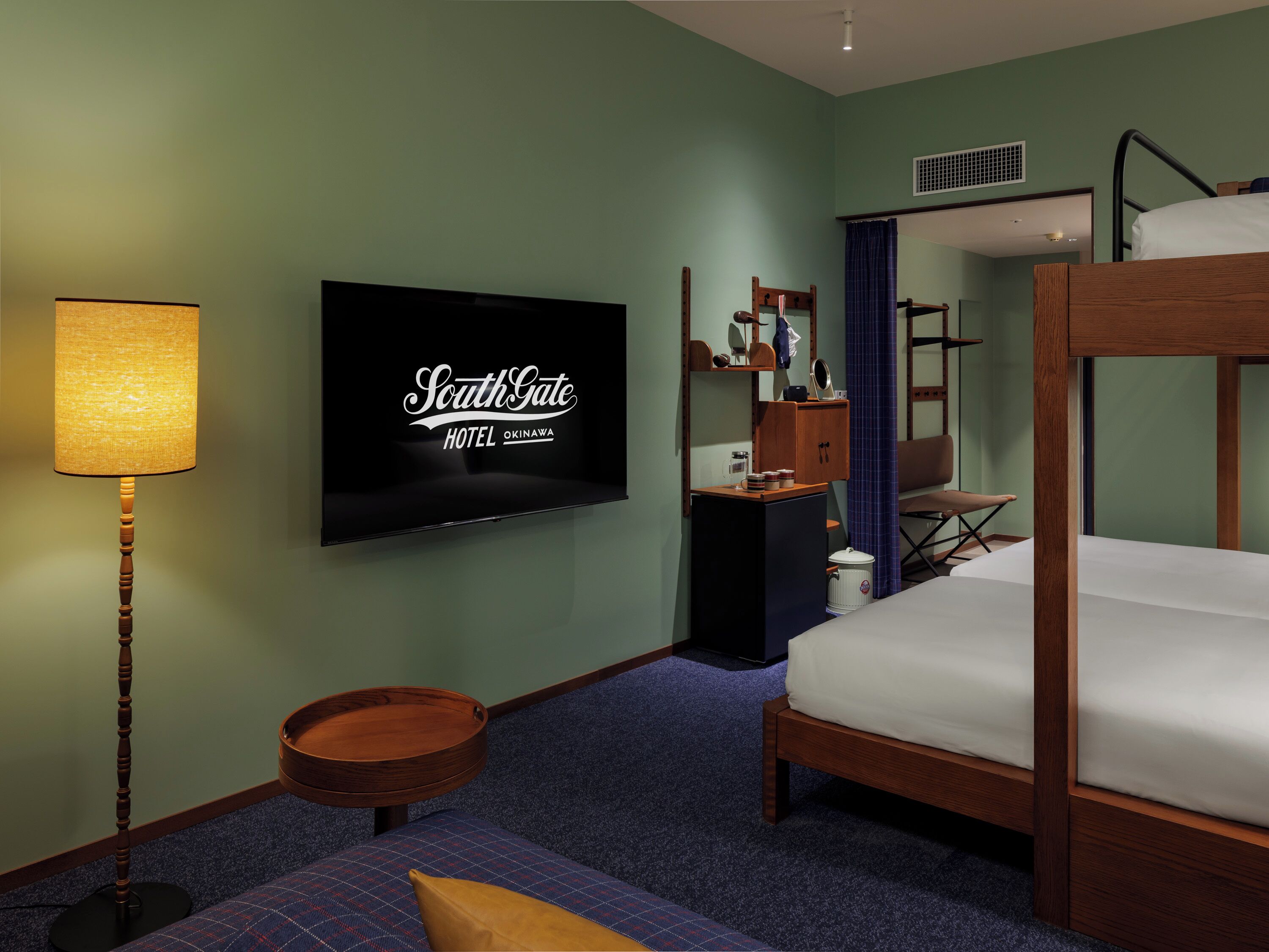 Une chambre d’hôtel comprenant un lit, une télévision, un bureau, une chaise, une lampe et une petite table ronde.