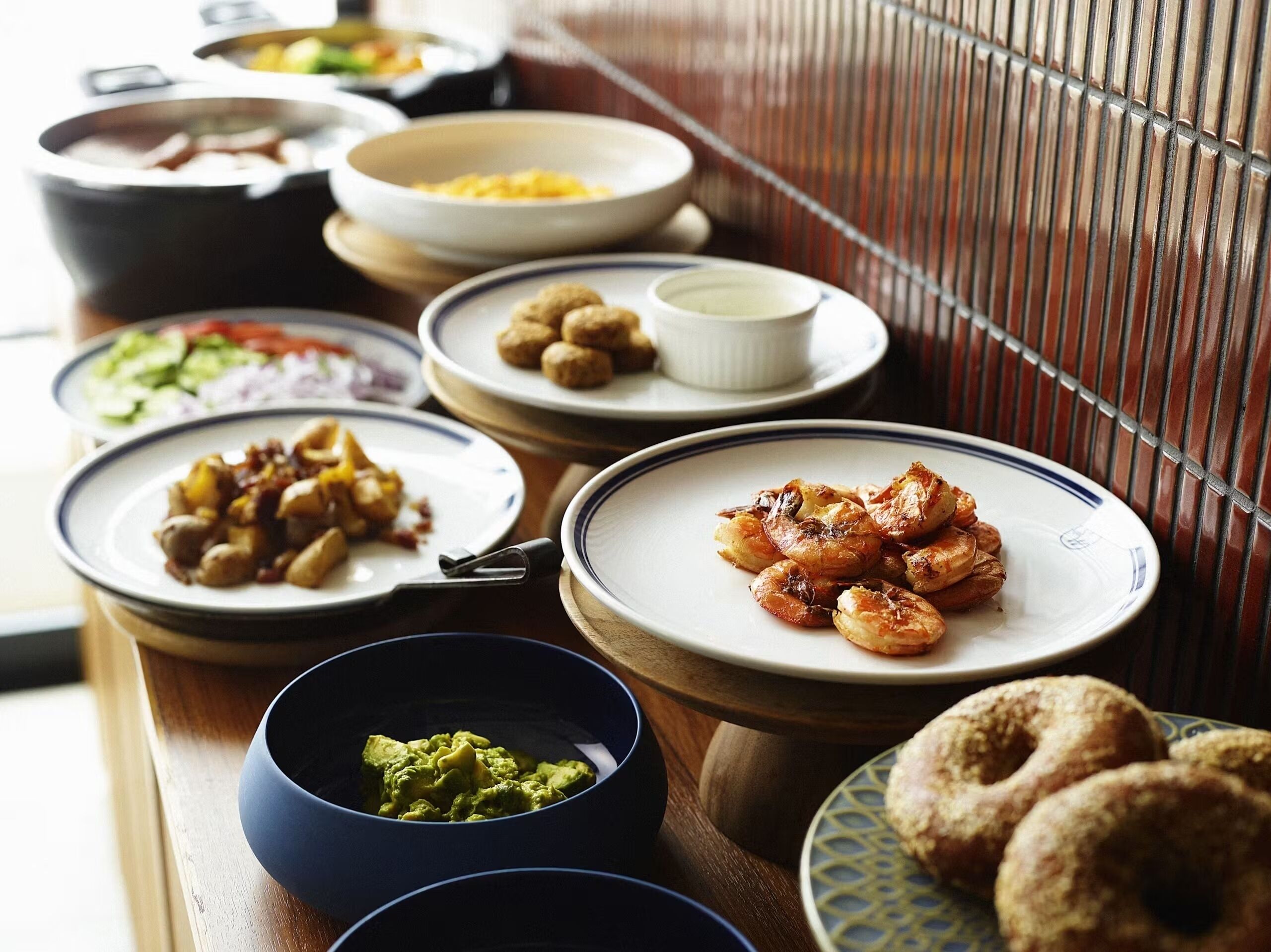 Una mesa de buffet con diversos platos, incluyendo camarones, aguacate y pasteles.