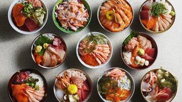 A variety of bowls containing different types of sashimi and seafood.