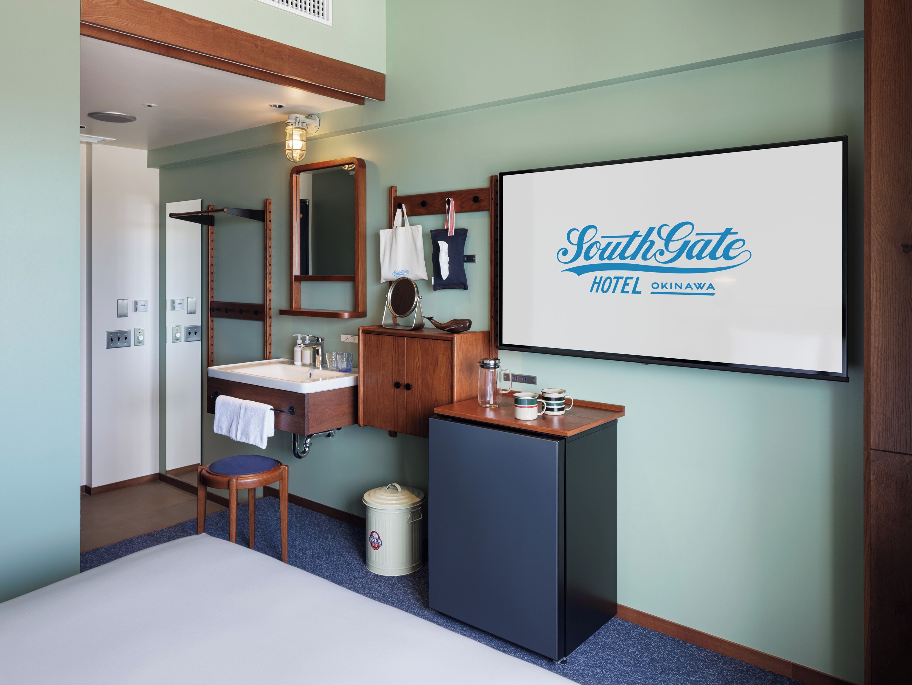 Hotelkamer met een bed, een wastafel, een spiegel, een klein kastje, een prullenbak en een bordje op de muur.