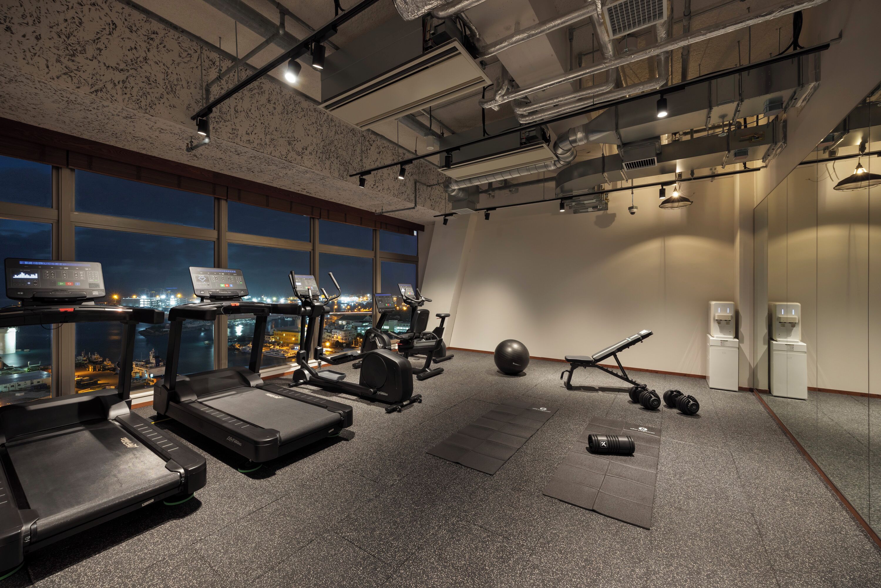 Ett gym med löpband, crosstrainers, en roddmaskin och hantlar.