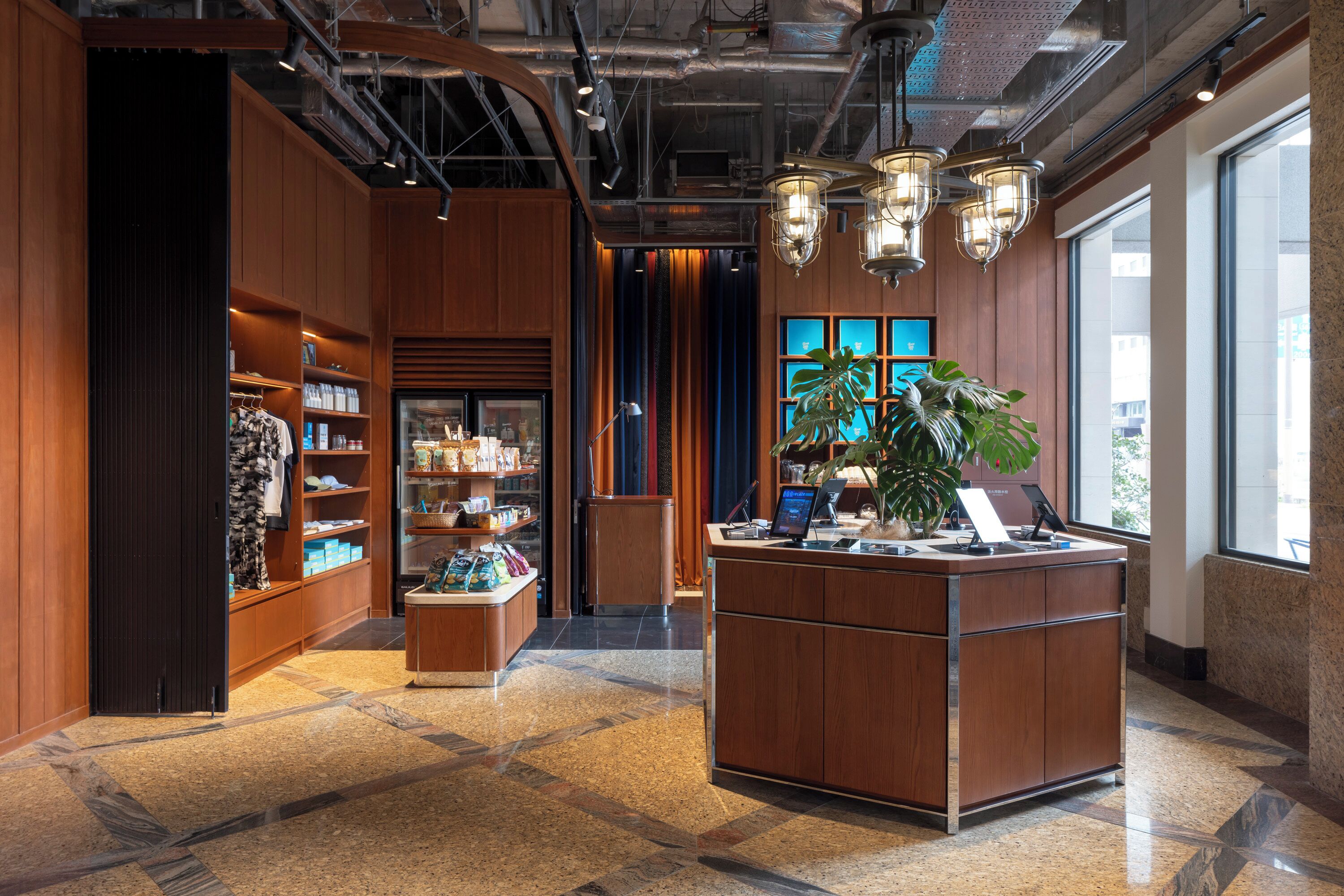 A lobby with a reception desk, wooden paneling, a large plant, and a window with a view.