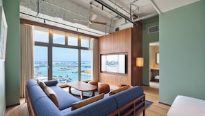 A hotel room with a large window, a sofa, a table, and a bed. - South Gate Hotel Okinawa Naha Tomari Port (Direct Access to Tomarin) (Naha)