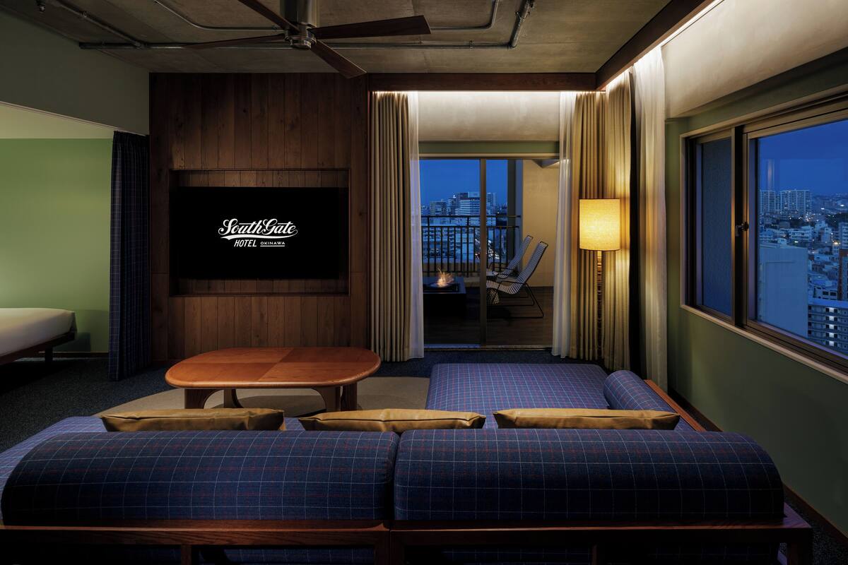 Habitación de hotel con televisor, sofá, mesa y vistas a la ciudad.