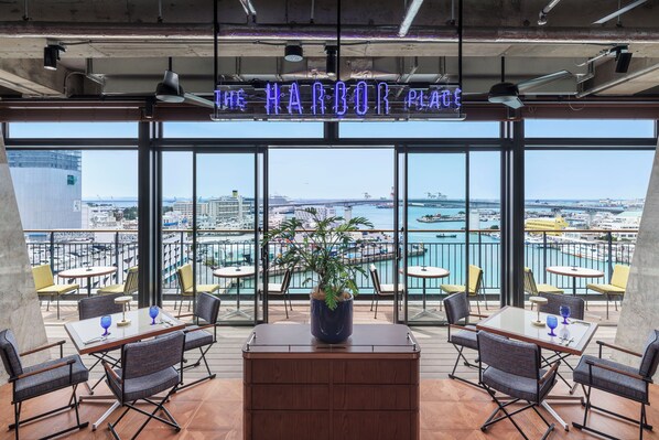 A restaurant with a view of the harbor, featuring a neon sign, outdoor seating, and a potted plant. - South Gate Hotel Okinawa Naha Tomari Port (Direct Access to Tomarin) (Naha)