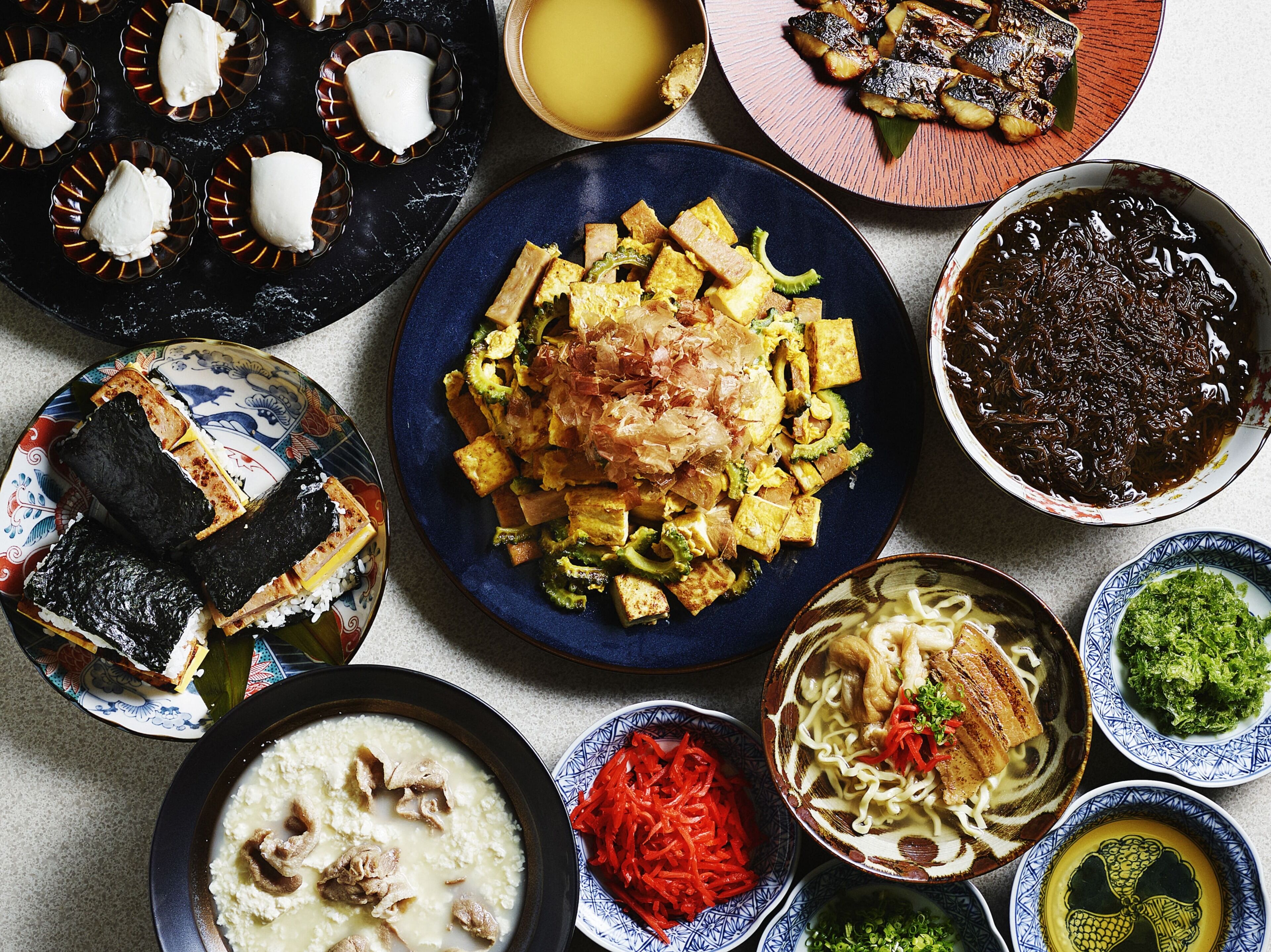 Une variété de plats sont disposés sur la table, notamment du tofu, des algues et des nouilles.