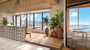 A modern interior with a wooden floor, large windows, and a view of the sea. - South Gate Hotel Okinawa Naha Tomari Port (Direct Access to Tomarin) (Naha)
