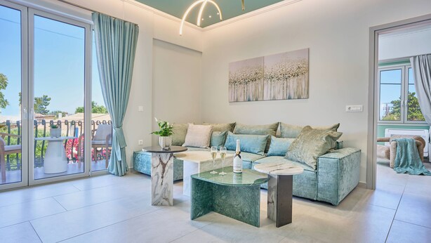 A modern living room with a sofa, coffee table, and a painting on the wall. - Bougainvillea Bliss (Σκαλα)