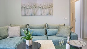A modern living room with a sectional sofa, a marble coffee table, and a green accent table. - Bougainvillea Bliss (Σκαλα)