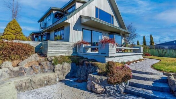 A modern two-story house with a prominent gable roof, large windows, and a stone pathway leading to the entrance. - Enjoy 180° views of Lake Tekapo (Lake Tekapo)