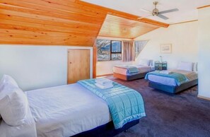 Un dormitorio con dos camas, techo de madera, una ventana y una puerta.