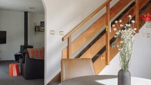 Una sala de estar moderna con una mesa redonda, una escalera de madera y vista a otra habitación.