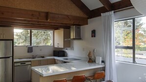 Una cocina moderna con vigas de madera, una isla grande y vistas a árboles al exterior.