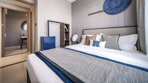 Una habitación de hotel moderna con una cama grande, una mesita de noche, un espejo y una obra de arte circular colgada en la pared.