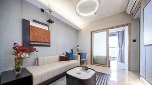 Una sala de estar moderna con un sofá, una mesa de centro y una mesita auxiliar con un florero. Hay una puerta que da a un balcón.