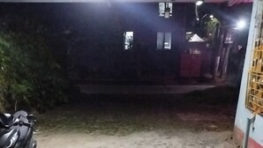 A dimly lit outdoor area with a concrete floor, a parked motorcycle, and a building in the background.