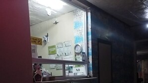 A dimly lit corridor with a counter displaying a 'NO REFUND' sign, a clock, and various notices on the wall.