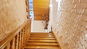 Una escalera de madera con una pared texturizada a un lado y una barandilla de madera al otro.