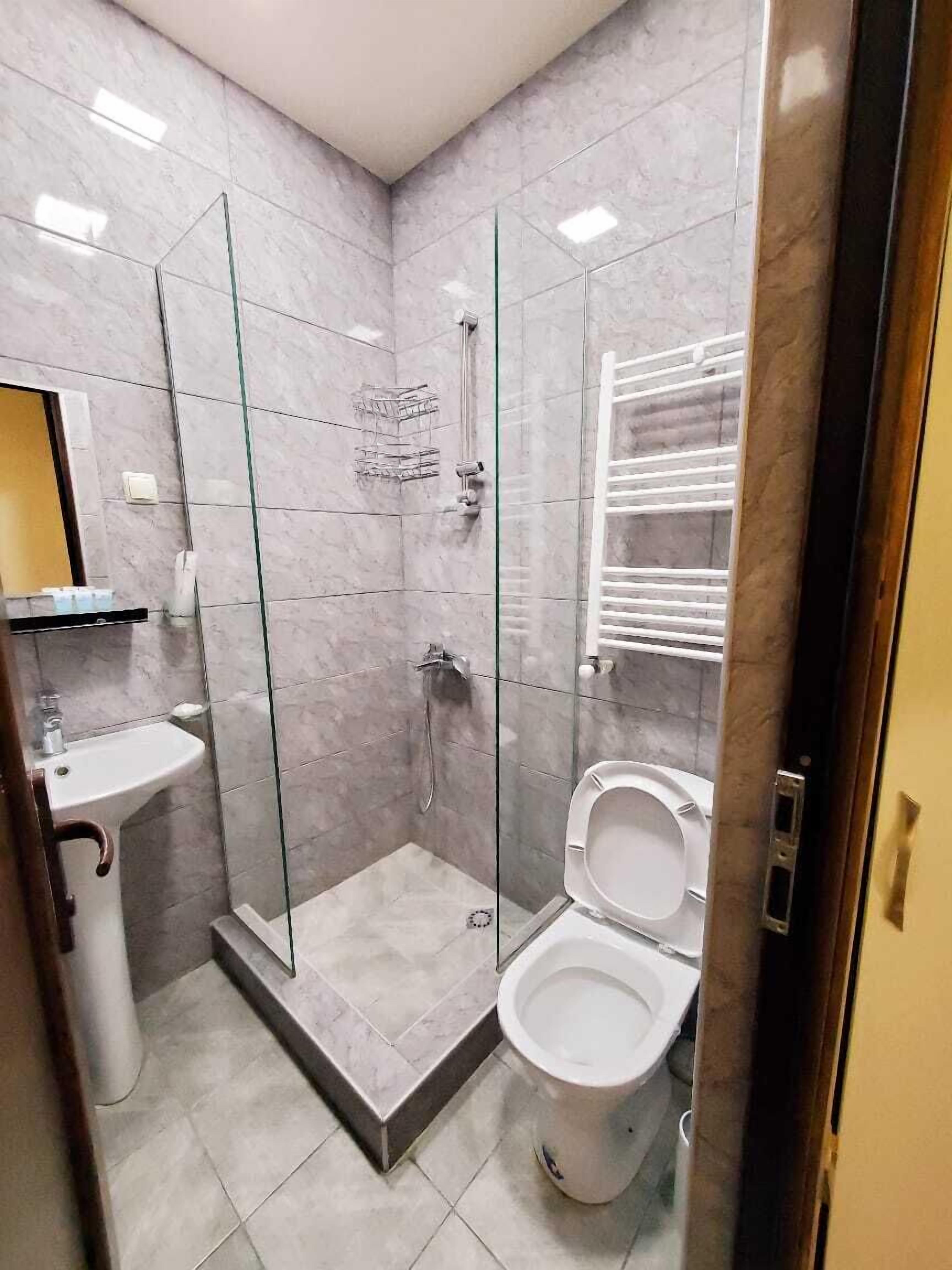A modern bathroom with a glass-enclosed shower, a toilet, and a sink.