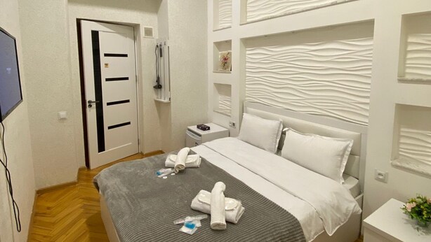 Una habitación de hotel con una cama, una mesita de noche, un televisor y una puerta.
