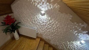Una habitación con techo de madera inclinado, un radiador blanco y una pared con motivo de panal.