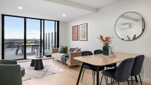 Un saló modern amb una finestra gran, una zona de menjador i un sofà.