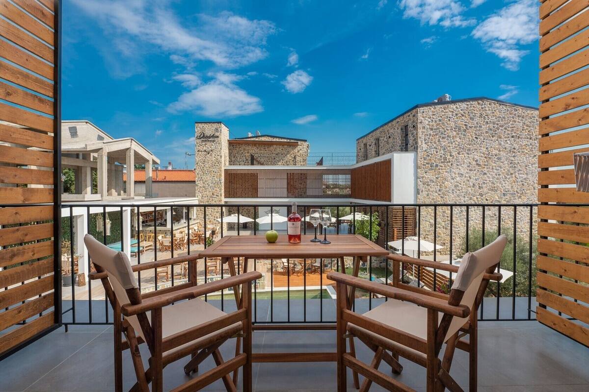 A balcony with a table and chairs, a bottle of wine, and a view of surrounding buildings.