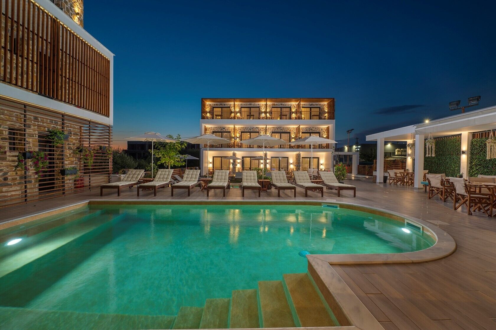A multi-story building with a pool area, outdoor seating, and a stone facade.