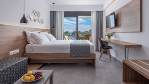 A modern hotel room with a bed, desk, and balcony view. - Dandelion Suites (Nikiti)
